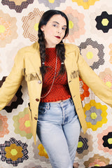 Men's or women's vintage 1950's long sleeve light tan colored genuine leather jacket with button front closure and fringe trim in front and back.