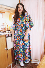 Women's vintage 1970's cotton material short sleeve maxi length dress with all over multicolored print. Has big flared sleeves and a V shaped neckline.