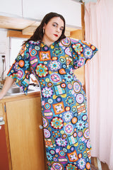 Women's vintage 1970's cotton material short sleeve maxi length dress with all over multicolored print. Has big flared sleeves and a V shaped neckline.