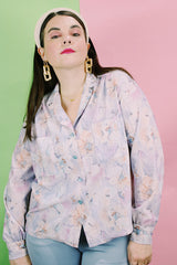 Women's vintage 1970's long sleeve button up blouse in an all over purple, blue, and pink floral print. Two chest pockets.