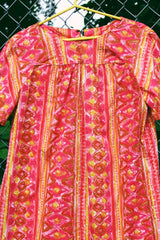 Women's vintage 1970's short sleeve midi length smock house dress in a pink, yellow, and light brown abstract print.