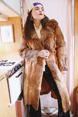 Women's vintage 1960's Apropos, Made in Korea label long sleeve knee length genuine fur coat with burnt orange leather trim and a tie belt.