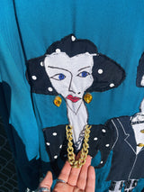 Women's vintage 1980's made in usa long sleeve blue blazer with one button closure and fully lined with large patches of people on front and back.