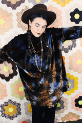 Long sleeve long length tie dye velvet top with a mock neck in a stretchy velvet material. Blue and brown colors with curly trim throughout.