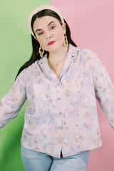 Women's vintage 1970's long sleeve button up blouse in an all over purple, blue, and pink floral print. Two chest pockets.