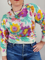 Women's vintage 1980's Sweater Teas label long sleeve white pullover acrylic sweater with all over large floral print in purple, yellow, and green.