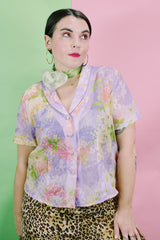 Women's vintage 1980's R&K Originals label short sleeve sheer button up blouse with all over purple and pink floral print with a slit in the back.