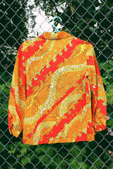 Women's vintage 1970's long sleeve button up blouse with dagger collar in an all over red, orange, and yellow vibrant abstract print.