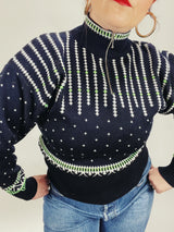 Women's vintage 1980's Demetre label long sleeve black pullover ski sweater with a half zip closure and white and green print all over.