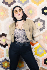 Women's vintage 1970's cropped fit tan suede jacket with short sleeves and two snap button closure in the front. Sleeves have a cream fur trim.