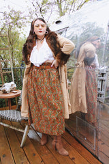 Women's vintage 1970's maxi length velvet skirt with an elastic waistband and matching tie belt. Orange with all over multicolored paisley print.