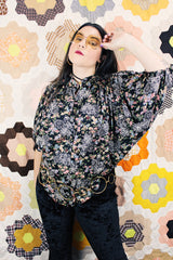Women's vintage 1970's lightweight polyester material black blouse with all over multicolored ditsy floral print. Buttons up the front and has big wing sleeves.