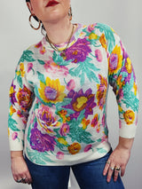 Women's vintage 1980's Sweater Teas label long sleeve white pullover acrylic sweater with all over large floral print in purple, yellow, and green.