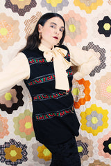 Women's vintage 1970's Palena Knitwear, Made in Hong Kong label sleeveless black wool vest with brass buckles closures up the front and floral trim details.