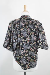 Women's vintage 1970's lightweight polyester material black blouse with all over multicolored ditsy floral print. Buttons up the front and has big wing sleeves.