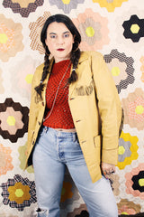 Men's or women's vintage 1950's long sleeve light tan colored genuine leather jacket with button front closure and fringe trim in front and back.