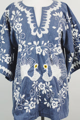 Women's vintage 1970's blue chambray tunic blouse with flared sleeves and a V shaped neckline. Has a white embroidered bird on the front.