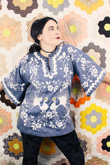 Women's vintage 1970's blue chambray tunic blouse with flared sleeves and a V shaped neckline. Has a white embroidered bird on the front.