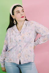 Women's vintage 1970's long sleeve button up blouse in an all over purple, blue, and pink floral print. Two chest pockets.