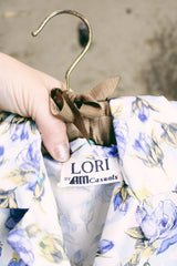 Women's vintage 1980's LORI by AM Casuals short sleeve button up blouse in white with all over blue floral print. Stretchy polyester material.