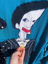 Women's vintage 1980's made in usa long sleeve blue blazer with one button closure and fully lined with large patches of people on front and back.