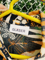 Women's vintage 1990's Glaser label short sleeve button up blouse with collar in a sheer material. All over black, white, and brown tropical flower print.