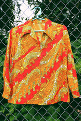 Women's vintage 1970's long sleeve button up blouse with dagger collar in an all over red, orange, and yellow vibrant abstract print.