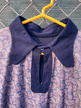 Women's or men's vintage 1970's long sleeve navy blue t-shirt with a paisley print on the front, a rounded dagger collar, and white popper buttons.