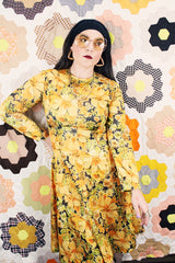Women's vintage 1970's long sleeve knee length dress in a lightweight polyester material. All over yellow and orange floral print.