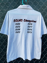 Women's or men's vintage 1970's short sleeve white polo t-shirt with half button closure and a graphic on the front left chest and one in the back.