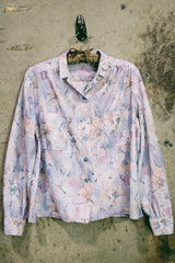 Women's vintage 1970's long sleeve button up blouse in an all over purple, blue, and pink floral print. Two chest pockets.
