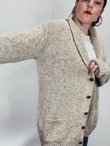 Men's vintage 1980's Rossan, Dongel Ireland, Hand Loomed in Ireland label long sleeve long length speckled cream colored button up cardigan with a rolled collar and brown buttons.