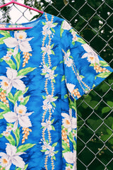 Women's vintage 1970's short sleeve Hawaiian print dress in blue with white flowers. Ruffle hem and maxi length.