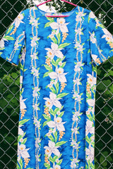 Women's vintage 1970's short sleeve Hawaiian print dress in blue with white flowers. Ruffle hem and maxi length.