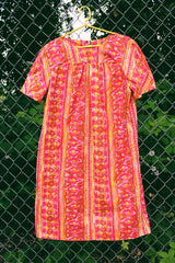 Women's vintage 1970's short sleeve midi length smock house dress in a pink, yellow, and light brown abstract print.