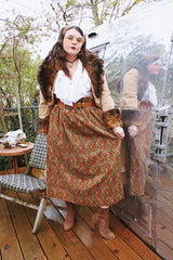 Women's vintage 1970's maxi length velvet skirt with an elastic waistband and matching tie belt. Orange with all over multicolored paisley print.