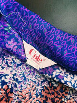 Women's vintage 1970's Cole of California label tie front blouse with balloon sleeves in purple, green, and orange colors and a lightweight polyester material.