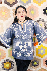 Women's vintage 1970's blue chambray tunic blouse with flared sleeves and a V shaped neckline. Has a white embroidered bird on the front.