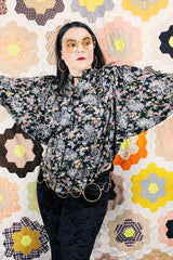 Women's vintage 1970's lightweight polyester material black blouse with all over multicolored ditsy floral print. Buttons up the front and has big wing sleeves.
