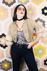 Women's vintage 1970's cropped fit tan suede jacket with short sleeves and two snap button closure in the front. Sleeves have a cream fur trim.