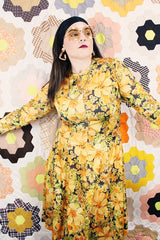 Women's vintage 1970's long sleeve knee length dress in a lightweight polyester material. All over yellow and orange floral print.