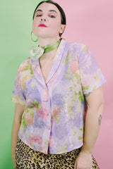 Women's vintage 1980's R&K Originals label short sleeve sheer button up blouse with all over purple and pink floral print with a slit in the back.