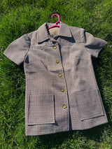 Women's vintage 1970's short sleeve button up shirt blouse in brown, white, and black gingham checkered polyester material with pockets.