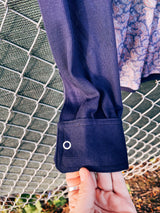 Women's or men's vintage 1970's long sleeve navy blue t-shirt with a paisley print on the front, a rounded dagger collar, and white popper buttons.