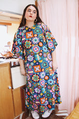 Women's vintage 1970's cotton material short sleeve maxi length dress with all over multicolored print. Has big flared sleeves and a V shaped neckline.