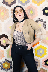 Women's vintage 1970's cropped fit tan suede jacket with short sleeves and two snap button closure in the front. Sleeves have a cream fur trim.