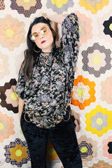 Women's vintage 1970's lightweight polyester material black blouse with all over multicolored ditsy floral print. Buttons up the front and has big wing sleeves.