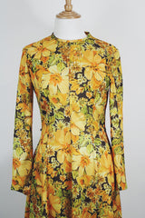 Women's vintage 1970's long sleeve knee length dress in a lightweight polyester material. All over yellow and orange floral print.