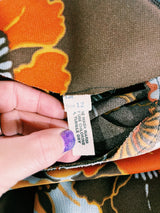 Women's vintage 1970's long sleeve knee length dress in a polyester material with a tie front neck. Brown color with all over yellow and orange flowers.