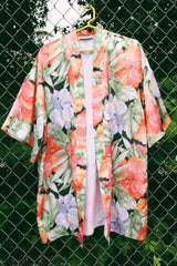Women's vintage 1990's Val Mode Lingerie, Made in USA label short sleeve short length loungewear robe in an all over tropical floral print in orange and green with a matching tie belt.